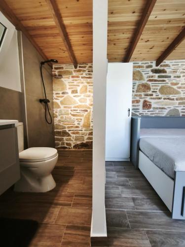 a bathroom with a toilet and a stone wall at KONSTANTINOS Luxury Living in Ofrínion