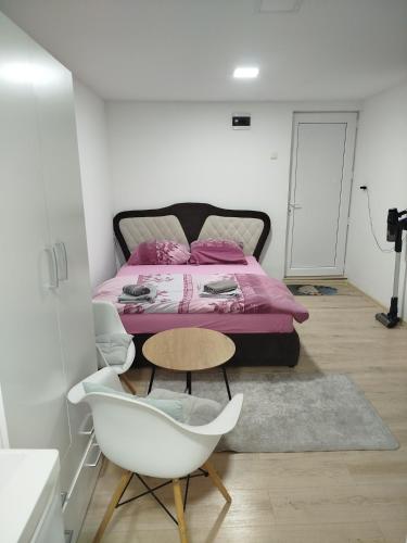 a bedroom with a bed and a chair and a table at Apartman Deni in Tuzla