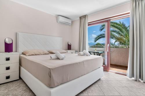 a white bedroom with a bed and a balcony at Villa Lili in Lovran