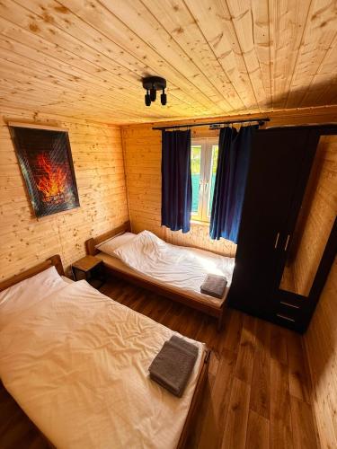 a bedroom with two beds in a room with wooden floors at By The Lake - Domki I Sauna Nad Jeziorem in Załęże