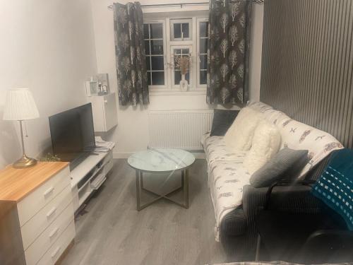 a living room with a couch and a tv at Room Younis in Tilehurst