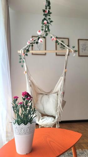 a hammock with a chair and flowers on a table at Happy One Park Apartment in Świdnica