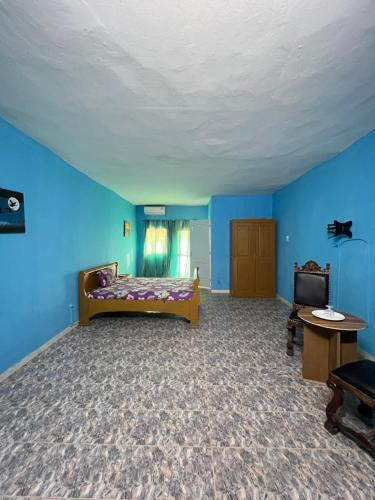 ein blaues Zimmer mit einem Bett und einem Fernseher in der Unterkunft Chalet rose in Toubab Dialao