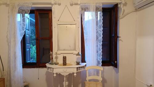 a room with two windows and a table and a mirror at George's house samos in Pagóndas