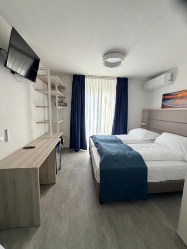 a bedroom with a bed and a desk with a television at Hotel Villa Mirella in Grado