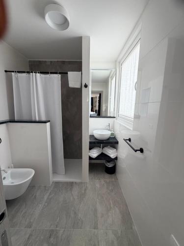 a white bathroom with a sink and a toilet at Hotel Villa Mirella in Grado