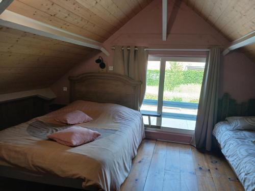 a bedroom with a bed with two pillows and a window at Le Chalet de Gonnehem in Gonnehem