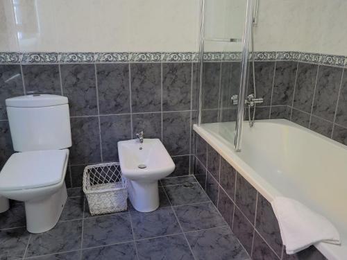 a bathroom with a toilet and a tub and a sink at Paraíso das Flores in Pataias