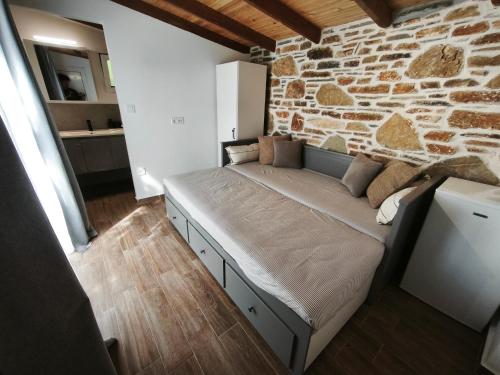 a bed in a room with a stone wall at KONSTANTINOS Luxury Living in Ofrínion