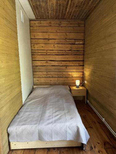 a small bedroom with a bed and a wooden wall at Võhma Külamaja, room nr 8 in Võhma