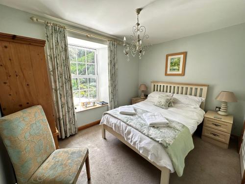 a bedroom with a bed and a chair and a window at The Waterwheel in St Austell
