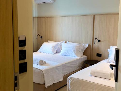 two beds in a hotel room with white sheets and pillows at RAI Rooms Saranda in Sarandë