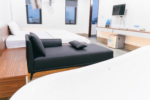 a living room with a black couch and a tv at R Hotell in Sầm Sơn