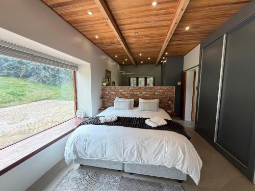 a bedroom with a large bed and a large window at Swiss Chalet Clarens in Clarens