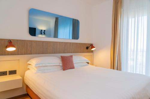 a bedroom with a white bed with a mirror on the wall at Le Rose Spa Hotel in Rimini