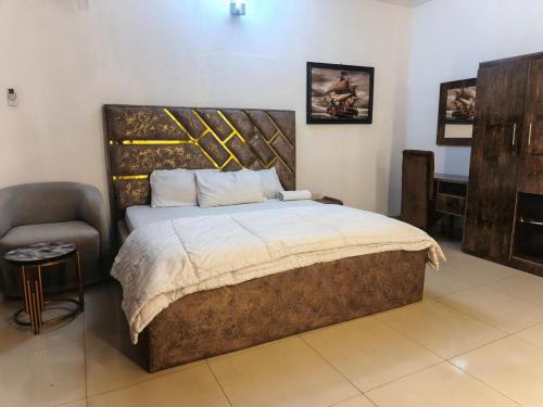 a bedroom with a large bed and a chair at Hillmabliz Apartment in Abuja