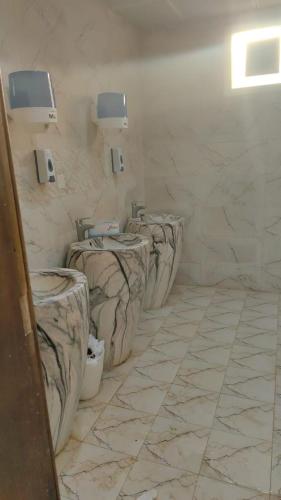 a row of three toilets in a bathroom at Alwahyada chalet in Majrá al Ghāf