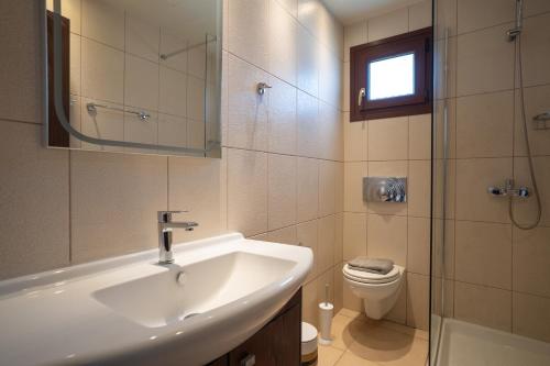 a bathroom with a sink and a toilet and a mirror at Agios Ioannis Cozy Houses With Private Pool in Tigaki