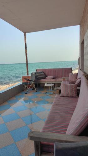 a room with couches and chairs on the beach at Alwahyada chalet in Majrá al Ghāf