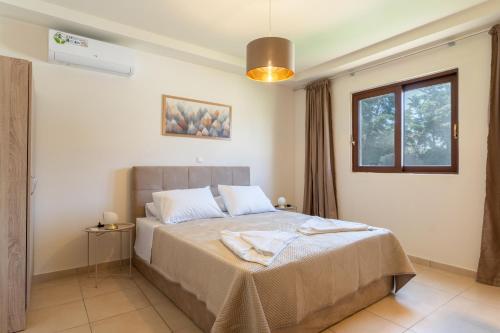a bedroom with a bed and a window at Agios Ioannis Cozy Houses With Private Pool in Tigaki