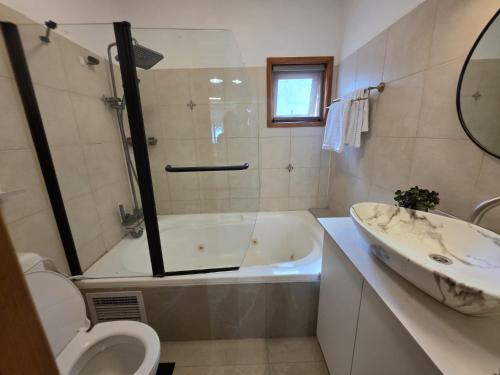 a bathroom with a tub and a sink and a toilet at הבקתות במושבה in Rosh Pinna
