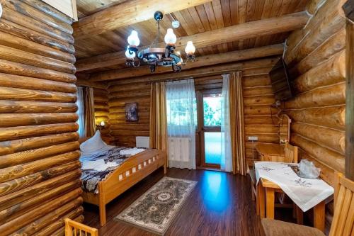 a bedroom in a log cabin with a bed and a table at Pensiunea Moeciu Casa Wiarusti in Moieciu de Sus