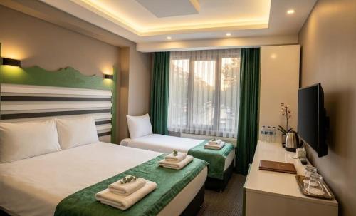 a hotel room with two beds and a desk and a television at David Moser 1878 Oteli in Kars