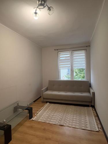 a living room with a couch and a window at Mieszkanie w Centrum Hajnówki-Brama Puszczy Białowieskiej in Hajnówka