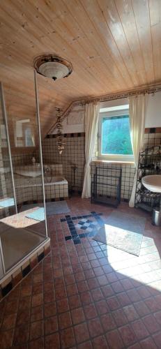 a large room with a wooden ceiling and a window at Haus Sonnhof in Herzogau