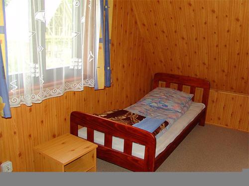 a small bed in a wooden room with a window at Leśna Polana in Baligród
