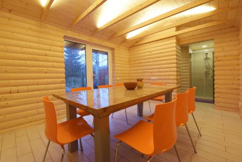 a wooden dining room with a table and orange chairs at Guest House Pasaulio Krastas in Palanga