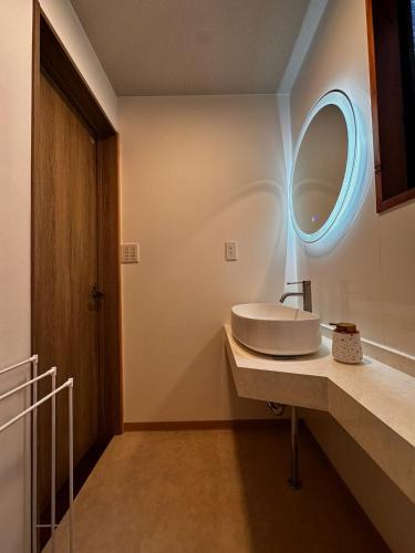 a bathroom with a sink and a round mirror at Maruta なんもく村 in Minamimaki