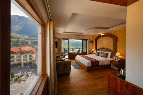 a hotel room with a bed and a large window at Manali Valley Resort in Manāli