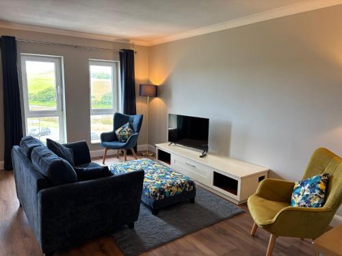 a living room with a couch and a tv and chairs at Harbour Mill Apartment in Westport