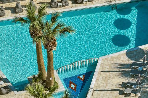 an overhead view of a swimming pool with palm trees at Hara Ilios Village in Gouves