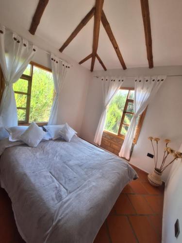 a bedroom with a large bed with two windows at Oasis Campestre in Sáchica