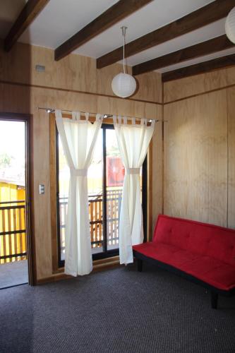 a living room with a red couch and windows at Kapai Departamentos de Turismo in Valdivia