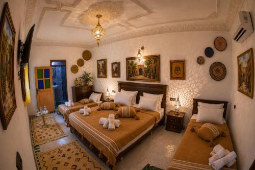 a bedroom with two beds and a chandelier at Riad T-A-J Fès Crown in Fez
