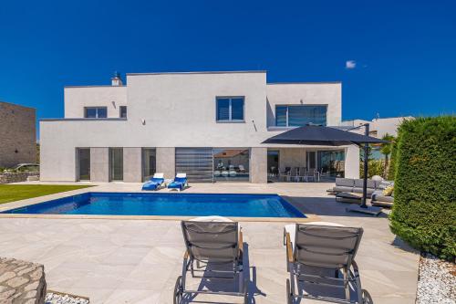 a house with a swimming pool and two chairs at Villa SIA with private pool in Krk