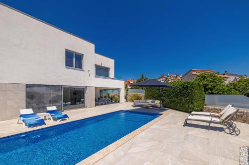 a swimming pool with chairs and a house at Villa SIA with private pool in Krk
