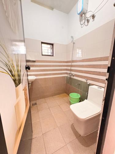 a bathroom with a toilet and a green bucket at Baylio Homestay in Kappil