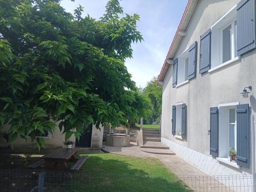 a building with a bench next to a tree at Le Gîte de la Gartempe in Saint-Sornin-la-Marche