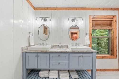 a bathroom with two sinks and a window at Twilight Pines - Dreamy Cabin w Hot Tub & optional Kids Loft in Broken Bow