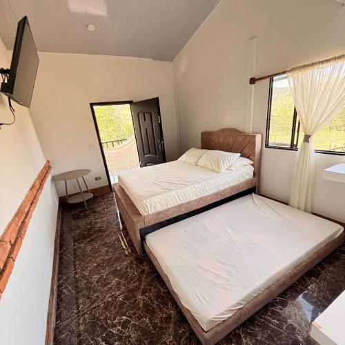 a bedroom with two beds and a tv in it at Villa Matilde in Curití
