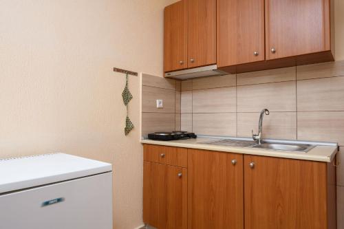 a kitchen with a sink and wooden cabinets at Qyra Studios in Skala Rachoniou