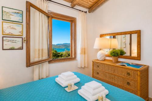 a bedroom with a blue bed with a window at Caprifogli Townhouse Close to the Beach in Baja Sardinia