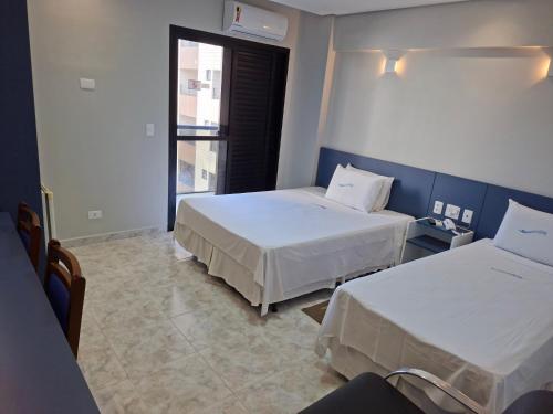 a hotel room with two beds and a window at HOTEL ROTA DO SOL in Praia Grande