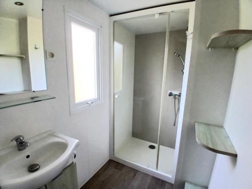 a white bathroom with a shower and a sink at Camping de Bourges in Bourges