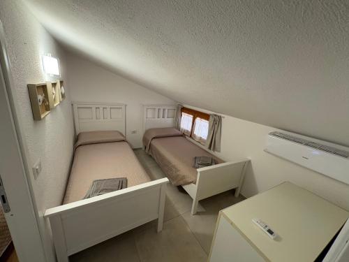 a small bedroom with two beds in a attic at Villa Anna in Costa Rei