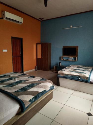 a bedroom with two beds and a tv on the wall at Amar mahal hotel and restaurant in Khātu